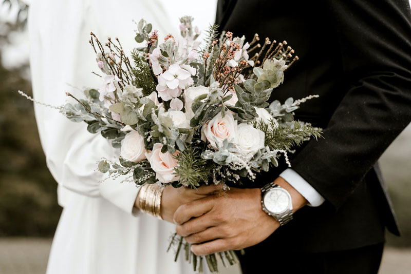 Newly married couple holding flowers, symbolizing love, joy, and the beginning of a beautiful journey together